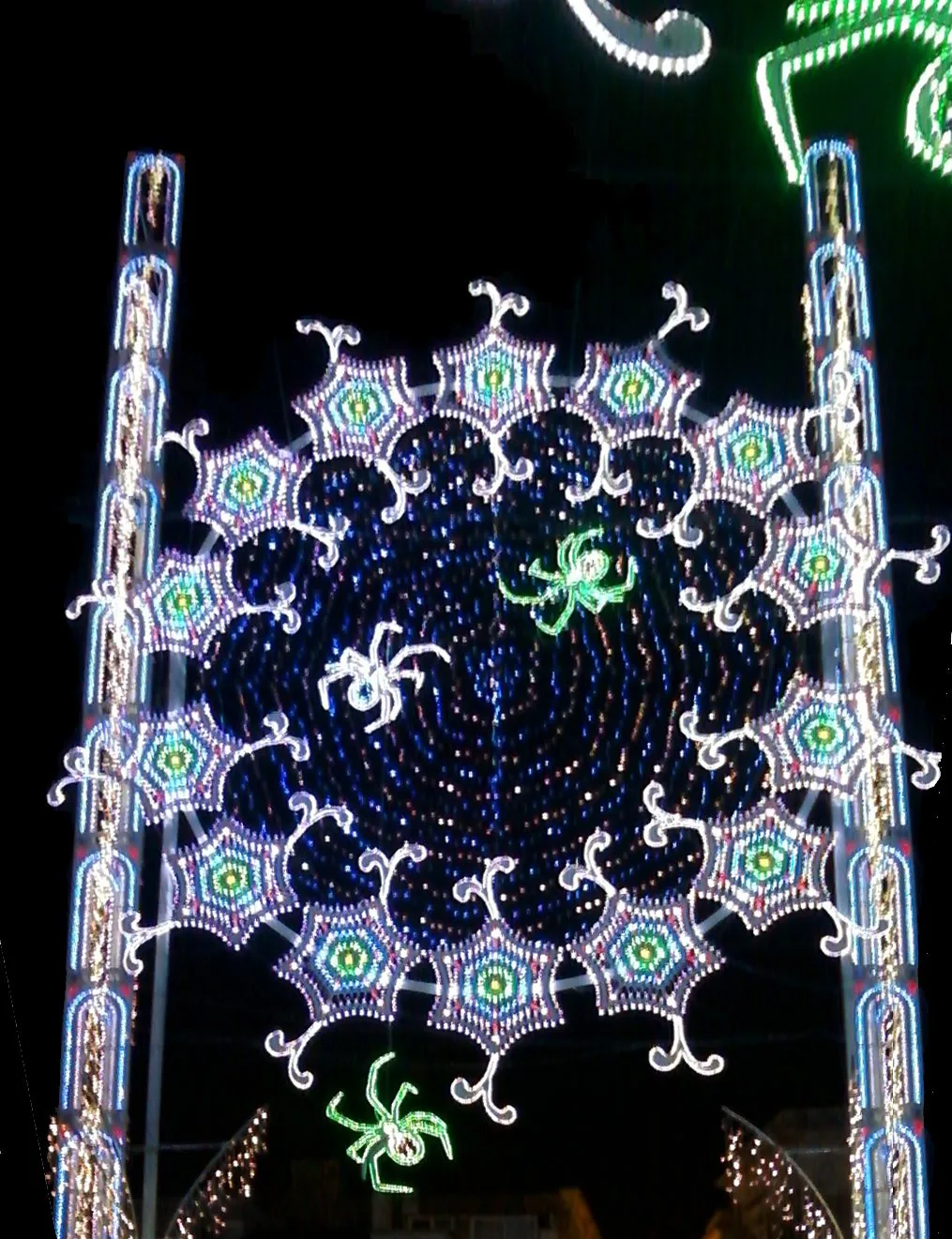 Luminarie monumentali accese sopra la strada di un paese salentino durante la festa patronale
